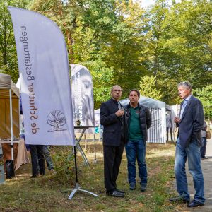 Banner im Vordergrund und Ronald de Schutter mit zwei weiteren Teilnehmern des Events Herbstwald erleben